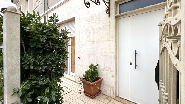 A narrow outdoor corridor with a potted plant, a white door, and a decorative metal fixture. - SE136 – Senigallia, brand new two-room apartment on the ground floor (Senigallia)