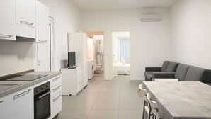 A modern kitchen with white cabinets, a built-in oven, and a dining area with a table and chairs. - SE136 – Senigallia, brand new two-room apartment on the ground floor (Senigallia)