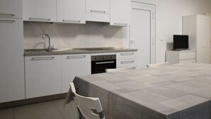 A modern kitchen with white cabinets, a built-in oven, and a dining area with a table and chairs. - SE136 – Senigallia, brand new two-room apartment on the ground floor (Senigallia)