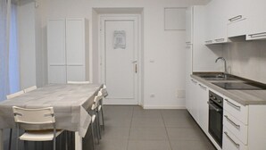 A compact kitchen with a dining table and chairs, a built-in oven, and a sink. - SE136 – Senigallia, brand new two-room apartment on the ground floor (Senigallia)