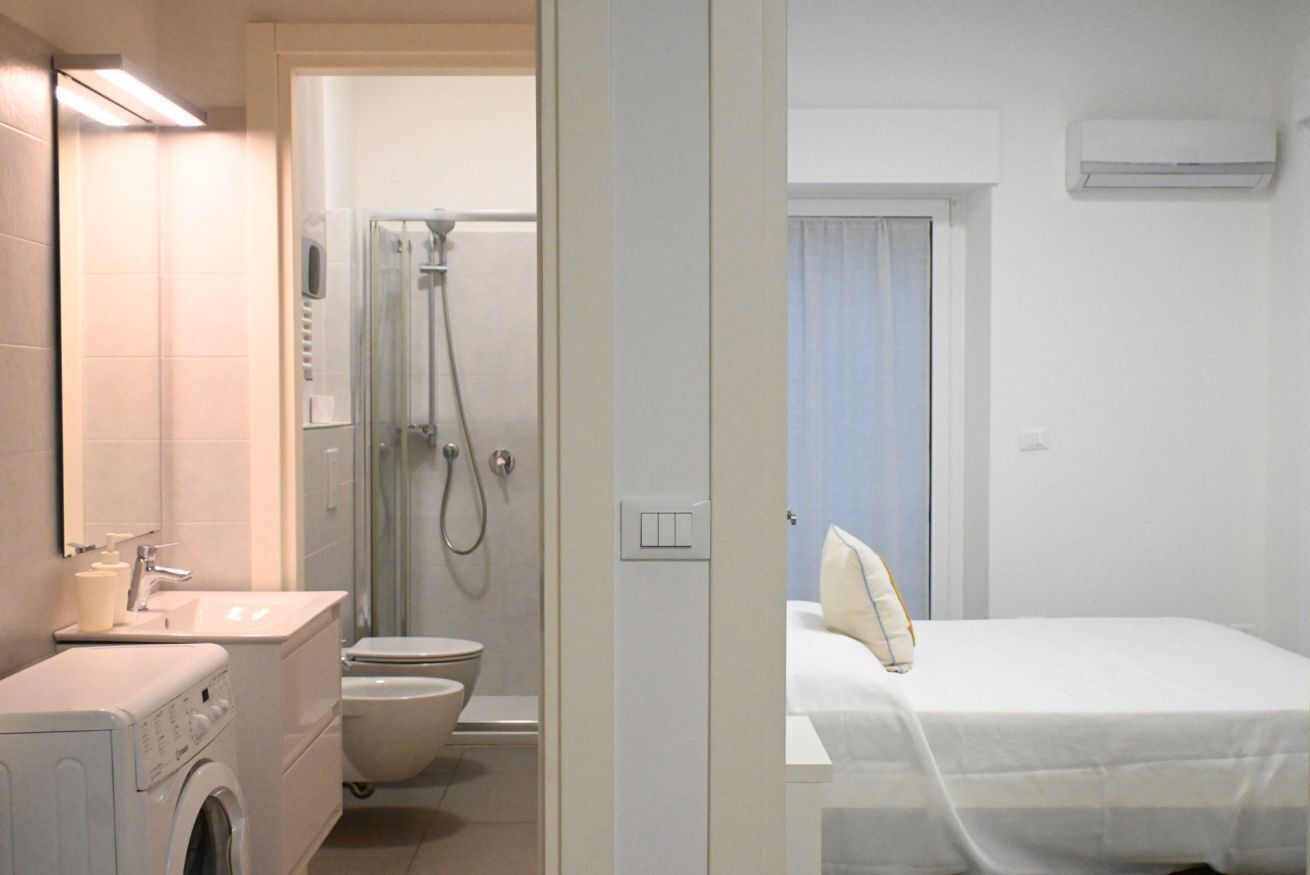 Ein Hotelzimmer mit Waschmaschine, Toilette, Dusche und Bett.