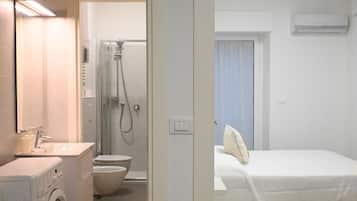 Ein Hotelzimmer mit Waschmaschine, Toilette, Dusche und Bett.
