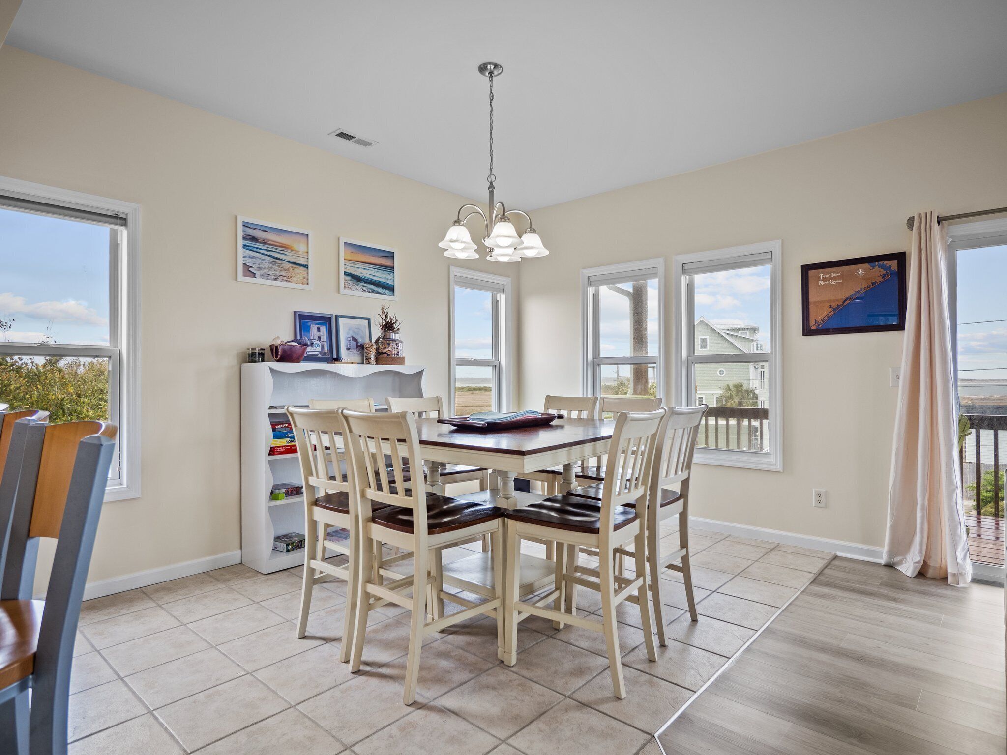 A dining area with a table and chairs, large windows, and artwork on the walls.