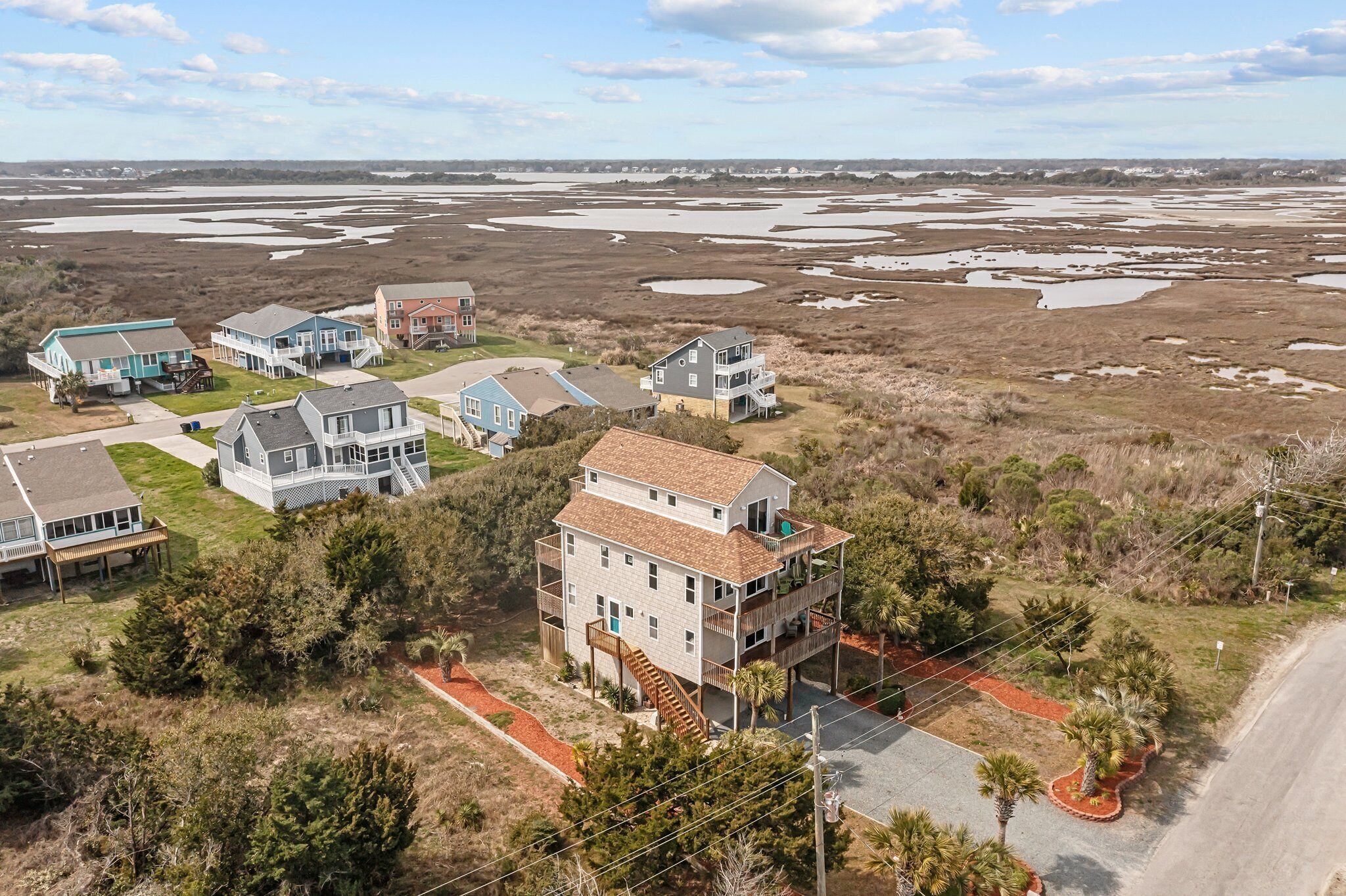 A coastal residential area with houses, a road, and a beach in the background.