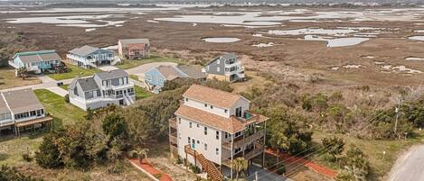 A coastal residential area with houses, a road, and a beach in the background.