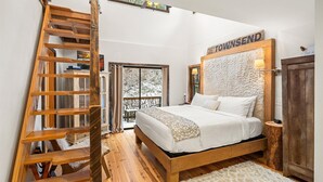 Une chambre avec une échelle en bois, un lit avec une literie blanche et une enseigne sur le mur portant l’inscription « TOWNSEND ».