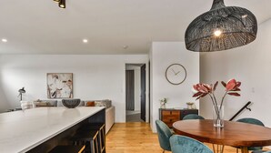 A modern kitchen with a central island, bar stools, a dining table with chairs, and a hanging light fixture. - Luxury accommodation close to the beach and main street. (Kingston SE)