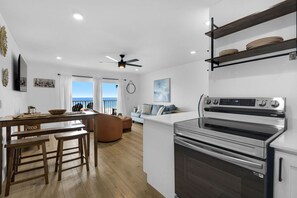 A modern kitchen with a built-in oven, wooden dining table with benches, and a view to the outside. - Summit 505 Beach Resort Condo - Balcony Best View (Panama City Beach)