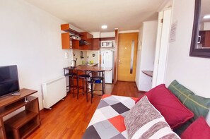 Un espacio habitable compacto con kitchenette, comedor y cama con colcha colorida.