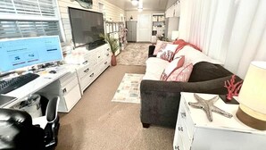 A compact living space with a kitchenette, a sofa, a desk with a computer, and a TV. - Charming 2-bedroom 1.5 Bath Cottage in the famous Sun Outdoors in Sarasota (Sarasota)