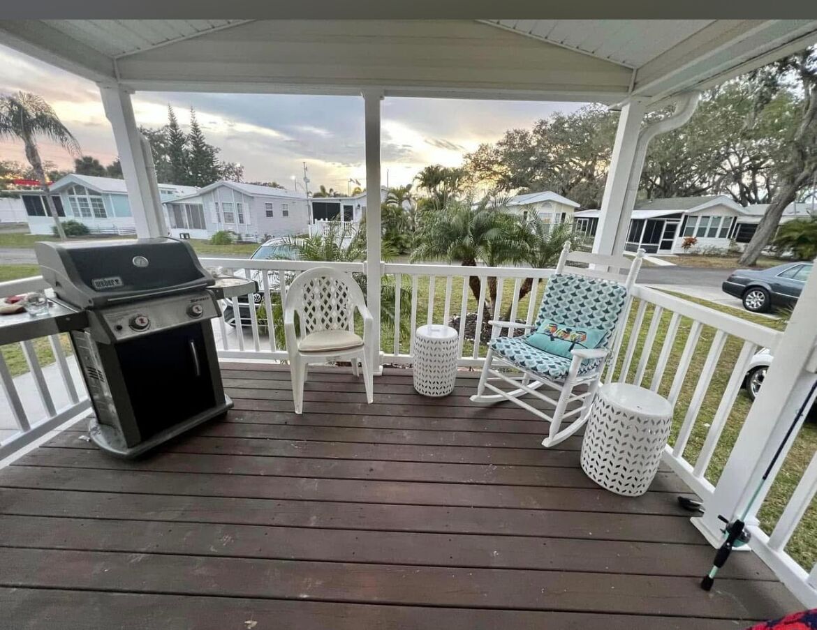 Une véranda abritée avec un barbecue, des chaises et une petite table.