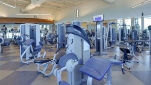 A gym with various exercise machines, a large mirror, and a digital screen. - Charming 2-bedroom 1.5 Bath Cottage in the famous Sun Outdoors in Sarasota (Sarasota)