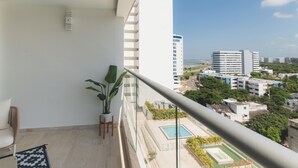 Un balcón con vistas a una piscina y edificios circundantes.