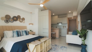 Un dormitorio moderno con una cama grande, un escritorio y una kitchenette.