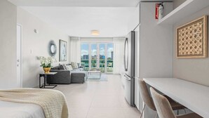 A modern apartment with a dining area, kitchenette, and a balcony with a city view. - Aqua Vista | Modern & Waterfront in Best Location (San Juan)