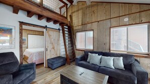 A loft-style room with a wooden floor, a sofa, a coffee table, and a staircase.
