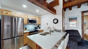 A modern kitchen with wooden cabinets, stainless steel appliances, and a white countertop.