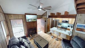 A spacious living area with a fireplace, a kitchen with modern appliances, and a dining area with bar stools.