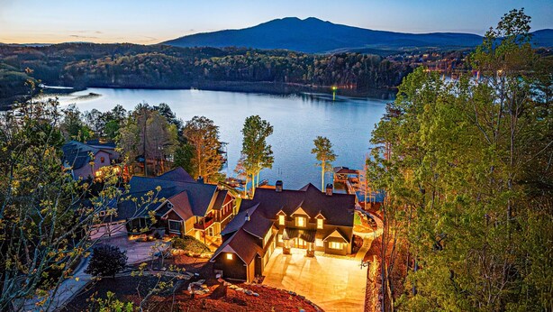 A lakeside property with multiple houses, a well-maintained garden, and a view of a lake and mountains in the background. - New Designer Lakefront Dock Putting Green Golf Sim (Nebo)