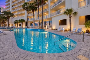 A hotel pool area with a clear blue pool, lounge chairs, and palm trees. - Admiral Quarters 705 | Beachfront | Indoor & Outdoor Pools | Beach Getaways (Orange Beach)
