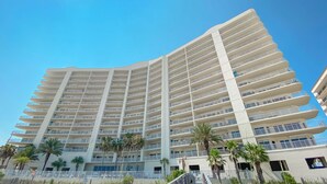 A multi-story hotel with a modern design, featuring balconies and a central walkway. - Admiral Quarters 705 | Beachfront | Indoor & Outdoor Pools | Beach Getaways (Orange Beach)