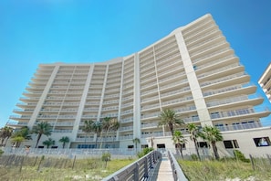 A multi-story hotel with balconies, palm trees, and a boardwalk.