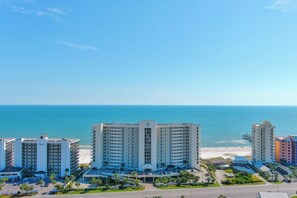 Un hotel de varios pisos, con entrada principal y vista a la playa y al océano.