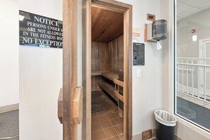 Un gimnasio con un banco de madera, dispensador de toallas y un cartel informativo.