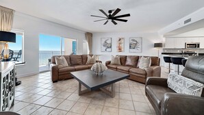 A modern living room with two brown leather sofas, a central coffee table, and a ceiling fan. - Admiral Quarters 705 | Beachfront | Indoor & Outdoor Pools | Beach Getaways (Orange Beach)