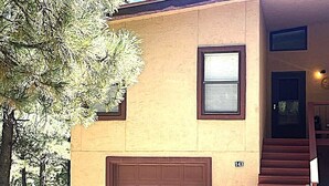 A two-story house with a brown garage door, a small window, and a staircase leading to the second floor. - Relax with the whole family or group of friends at this cozy Behr Hideout! (Alto)