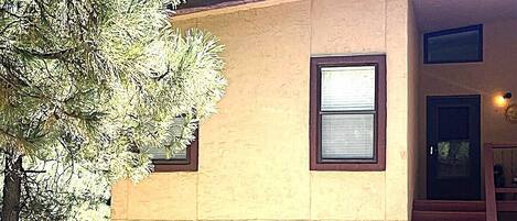 Una casa de dos pisos con una puerta de garaje marrón, una ventana pequeña y una escalera que sube al segundo piso.