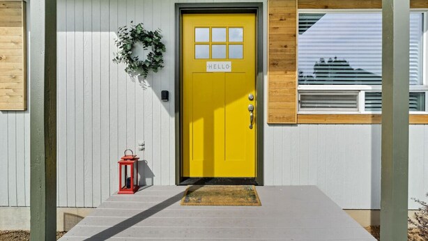 A building with a yellow door, a number plaque, and a red lantern.