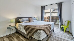 A bedroom with a bed, bedside lamps, a small table, and a chair.