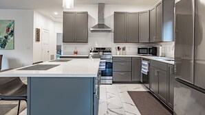 Una cocina moderna con armarios grises, electrodomésticos de acero inoxidable y una isla central.