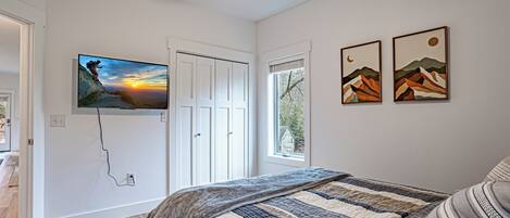 A bedroom with a bed, a television mounted on the wall, and two framed pictures.