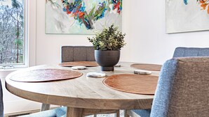 Una mesa redonda de comedor con una planta en maceta en el centro, rodeada de caminos de mesa y sillas a juego.