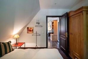 A bedroom with a bed, bedside table, lamp, and wardrobe.