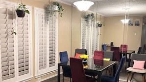 A dining area with a table and chairs, a hanging plant, and a ceiling light.