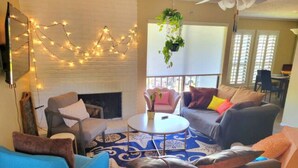 A cozy living room with a fireplace, comfortable seating, and string lights.