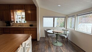 A spacious kitchen with wooden cabinets, a large island, and a dining area with a round table and chairs. - The Garden Hideaway! East Medford, close to hospital, shopping and restaurants.  (Medford)