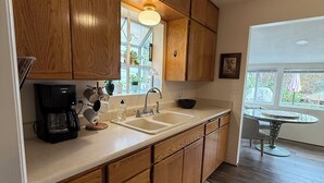 A kitchen with wooden cabinets, a coffee maker, a sink, and a window with a view of the outdoors. - The Garden Hideaway! East Medford, close to hospital, shopping and restaurants.  (Medford)