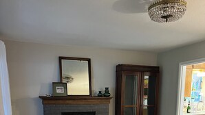 A living room with a fireplace, a large cabinet, and a sofa. - The Garden Hideaway! East Medford, close to hospital, shopping and restaurants.  (Medford)