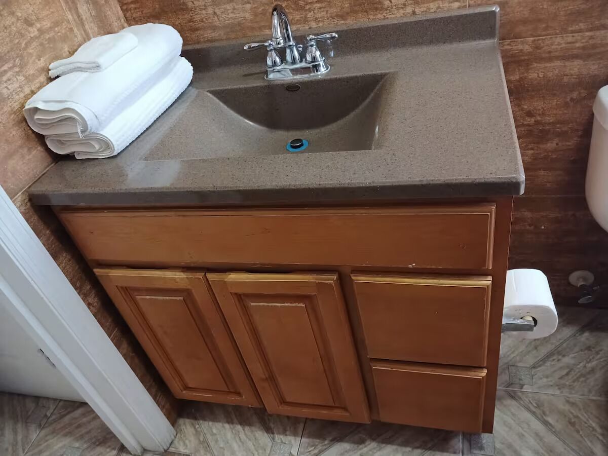 Un bagno con lavandino, asciugamano e carta igienica.