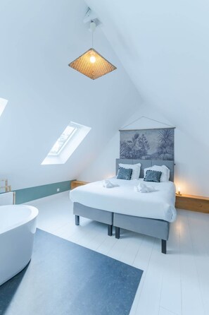 Ein modernes Schlafzimmer mit Bett, Nachttisch, Wandbild und Oberlichter.
