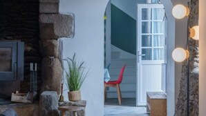 Una sala de estar acogedora con chimenea de piedra, un rincón de estar confortable y vistas a una habitación luminosa a través de un arco.