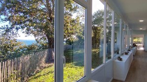 A modern interior with large windows offering a view of a garden and a wooden fence.
