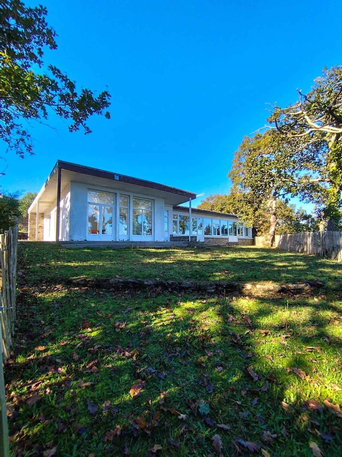 A modern two-story house with large windows and a well-maintained lawn.