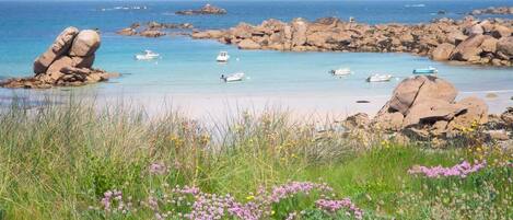 A coastal landscape with rocky formations, clear blue water, and boats.