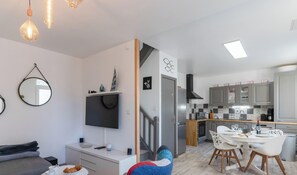 A modern apartment with a living room, dining area, kitchen, and a staircase.