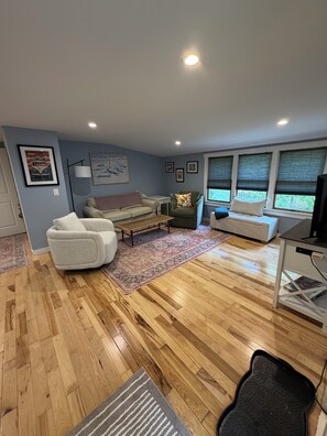 A living room with a sofa, armchairs, a coffee table, and a TV stand. - Newly renovated 3BR house, FREE CAR with beach sticker, pet friendly, sleeps 10. (West Tisbury)